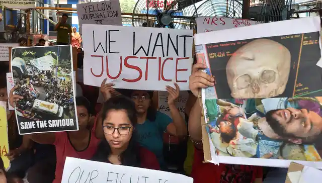 Junior doctors hold placards during a demonstration after an intern doctor was attacked and seriously injured over the death of a 75-year-old patient, at Nil Ratan Sircar Medical College and Hospital, in Kolkata on Thursday, 13 June.