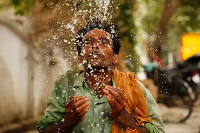 An Indian worker splashes water on his face to cool himself on a hot summer afternoon in Prayagraj, Uttar Pradesh, India, on Thursday, 13 June.