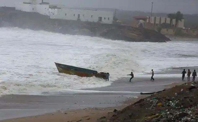 Fishermen try to control their boat amidst rough sea waters at Veraval, in Gir Somnath, Thursday, June 13, 2019.