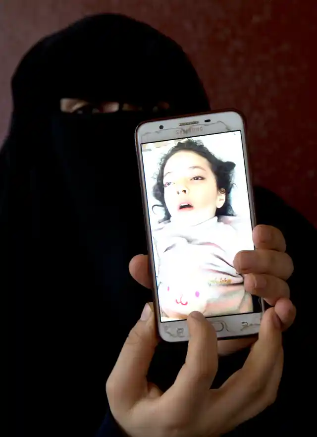 Aisha’s mother shows a picture of her daughter in the hospital bed.