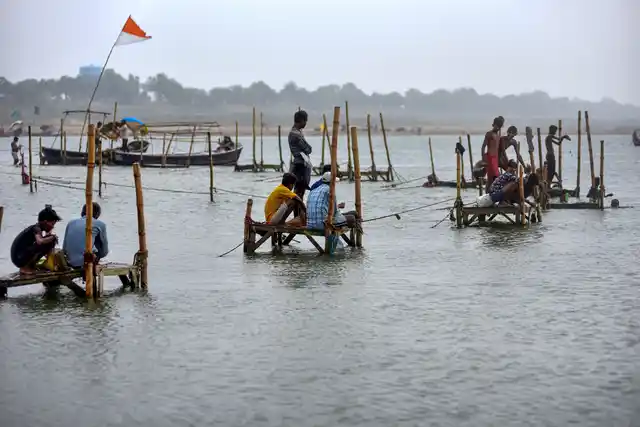 Fishermen catch fish from River Ganga following rainfall, in Prayagraj on Wednesday, 3 July.