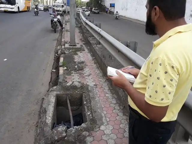 Mr Irfan Machhiwala takes note of an open manhole near the highway. 