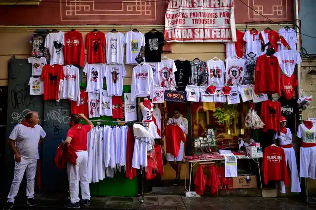 Three men dressed in white and red clothes stand beside San Fermin’s shop at the San Fermin Festival, in Pamplona, northern Spain.