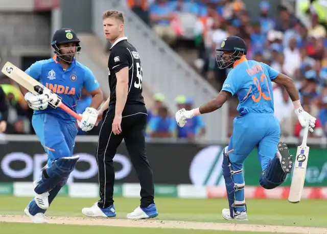New Zealand’s James Neesham, center, watches as India’s Hardik Pandya, right, and Rishabh Pant run between the wickets to score during the Cricket World Cup semi-final.
