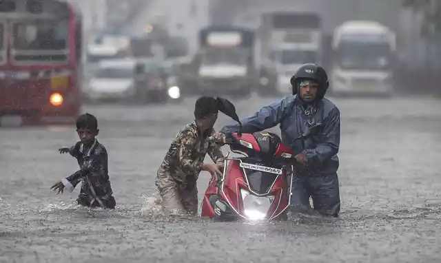 Commuters wade through a waterlogged street during heavy monsoon rain in Ghatkopar in Mumbai on Tuesday, 2 July. 