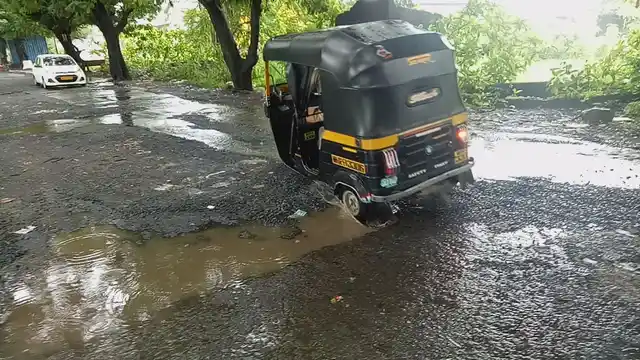 An auto tries to drive through a pothole at Royal Palm road, in Aarey Colony, Goregaon East. 