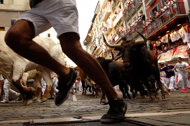 People run next to fighting bulls from Cebada Gago ranch, during the running of the bulls at the San Fermin Festival, in Pamplona.