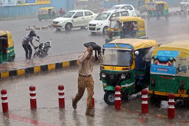 A pedestrian takes cover during heavy pre-monsoon rainfall in Noida on Friday, 5 July.