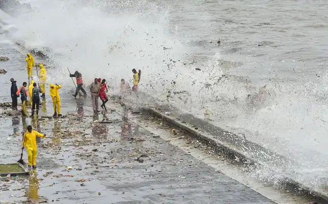Civic body workers clear the debris of plastic waste and garbage thrown out from the sea during a high tide at Marine Drive promenade, in Mumbai on Sunday, 7 July.