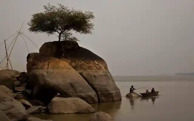 In this Monday, 21 Oct 2019, file photo, a fisherman sits on a rock to catch fish in the river Brahmaputra in Kasoshila village on the outskirts of Gauhati, India.