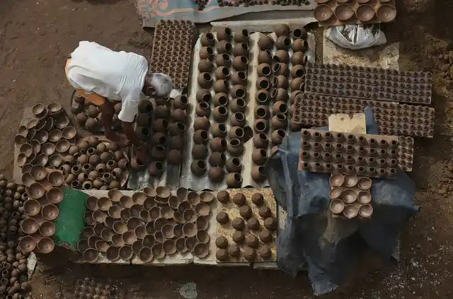 An Indian potter arranges earthen lamps to dry for the upcoming Diwali festival in Hyderabad, India, Tuesday, 22 Oct 2019.