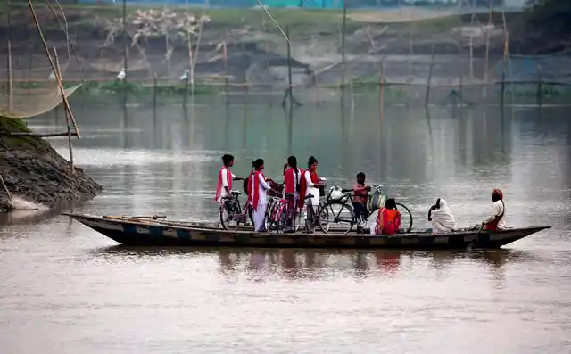 School children ride on a boat with their bicycles to cross the river Brahmaputra in Kasoshila village on the outskirts of Gauhati, India, Monday, 21 Oct 2019.