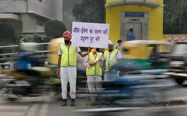 Volunteers wear pollution masks as they stand at a busy crossing with the banner saying obey odd and even, remove pollution, in New Delhi.