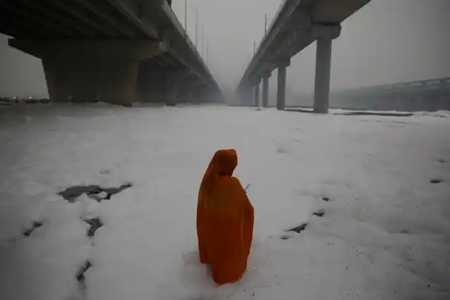 An Indian Hindu devotee performs rituals in Yamuna river, covered by chemical foam caused due to industrial and domestic pollution, during Chhath Puja festival in New Delhi.
