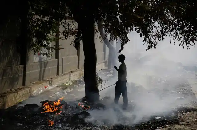 A ragpicker boy stand next to burning garbage on the outskirts of Delhi.