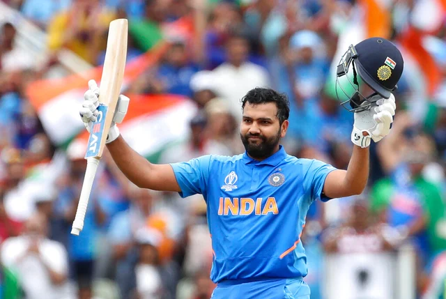 India's Rohit Sharma raises his bat and helmet to celebrate scoring a century.