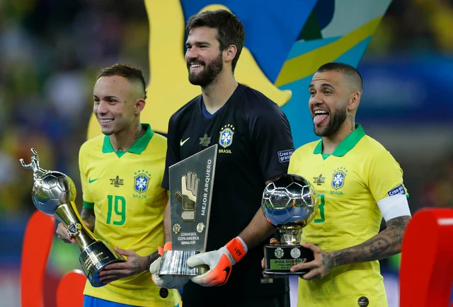Brazil's Everton, left, holds his Top Scorer trophy as he poses with teammates goalkeeper Alisson holding his Best Goalkeeper trophy and Brazil's Dani Alves holding his top scorer trophy.