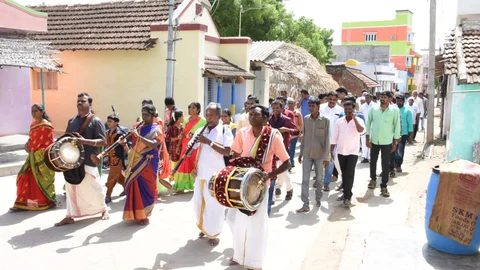 ஆசிரியர்களை ஊர்வலமாக அழைத்துவரும் மாணவர்கள்.