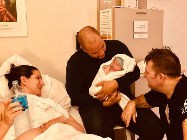 Dads with surrogate mother and baby