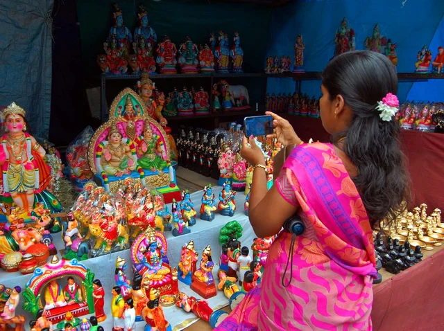 கொலு பொம்மைகளை ஆர்வமுடன் மொபைலில் படம் பிடிக்கும் பெண்