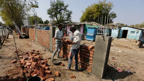 workers construct a wall in front of a slum in Ahmedabad