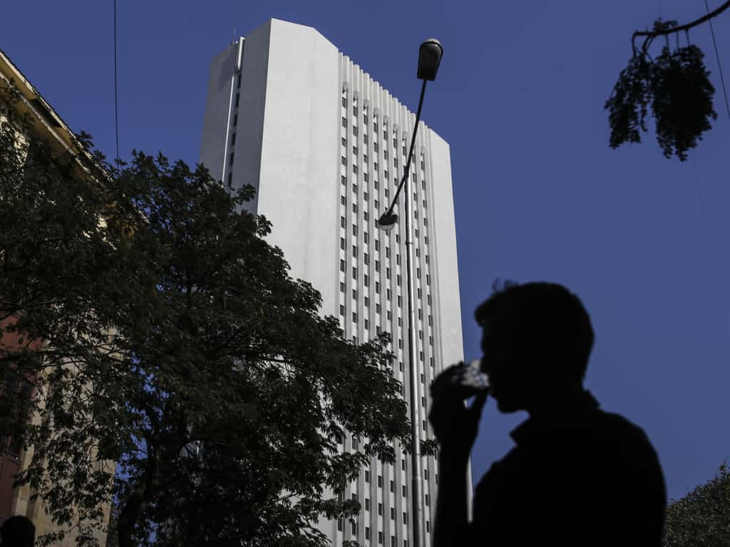 A man drinks tea as he walks past the Reserve Bank of India (RBI) headquarter building in Mumbai. (Photographer: Dhiraj Singh/Bloomberg)