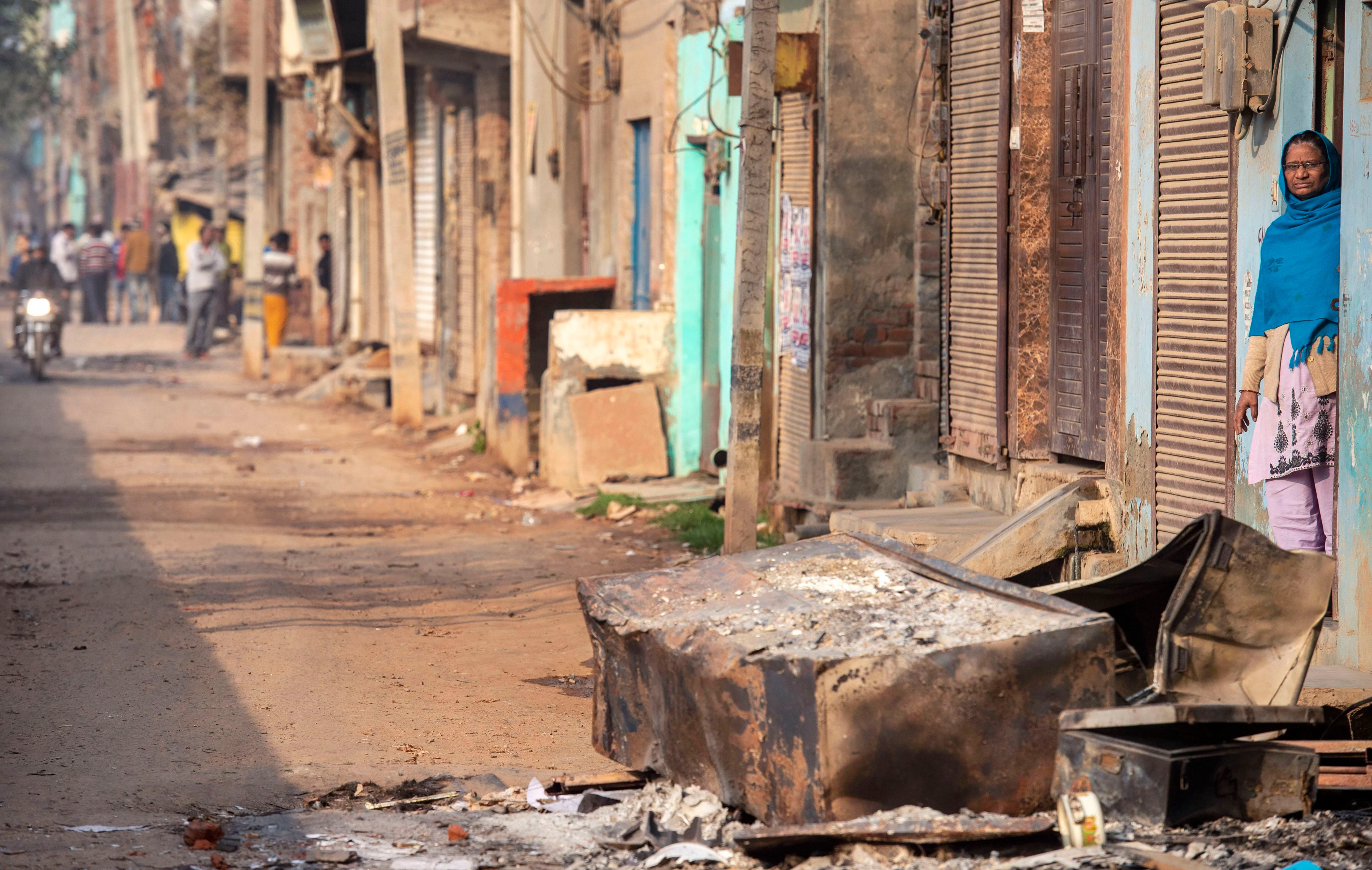 A woman stands near charred remains of vandalised property set ablaze by rioters in northeast Delhi on Thursday, Feb. 27, 2020. (Photo: PTI)