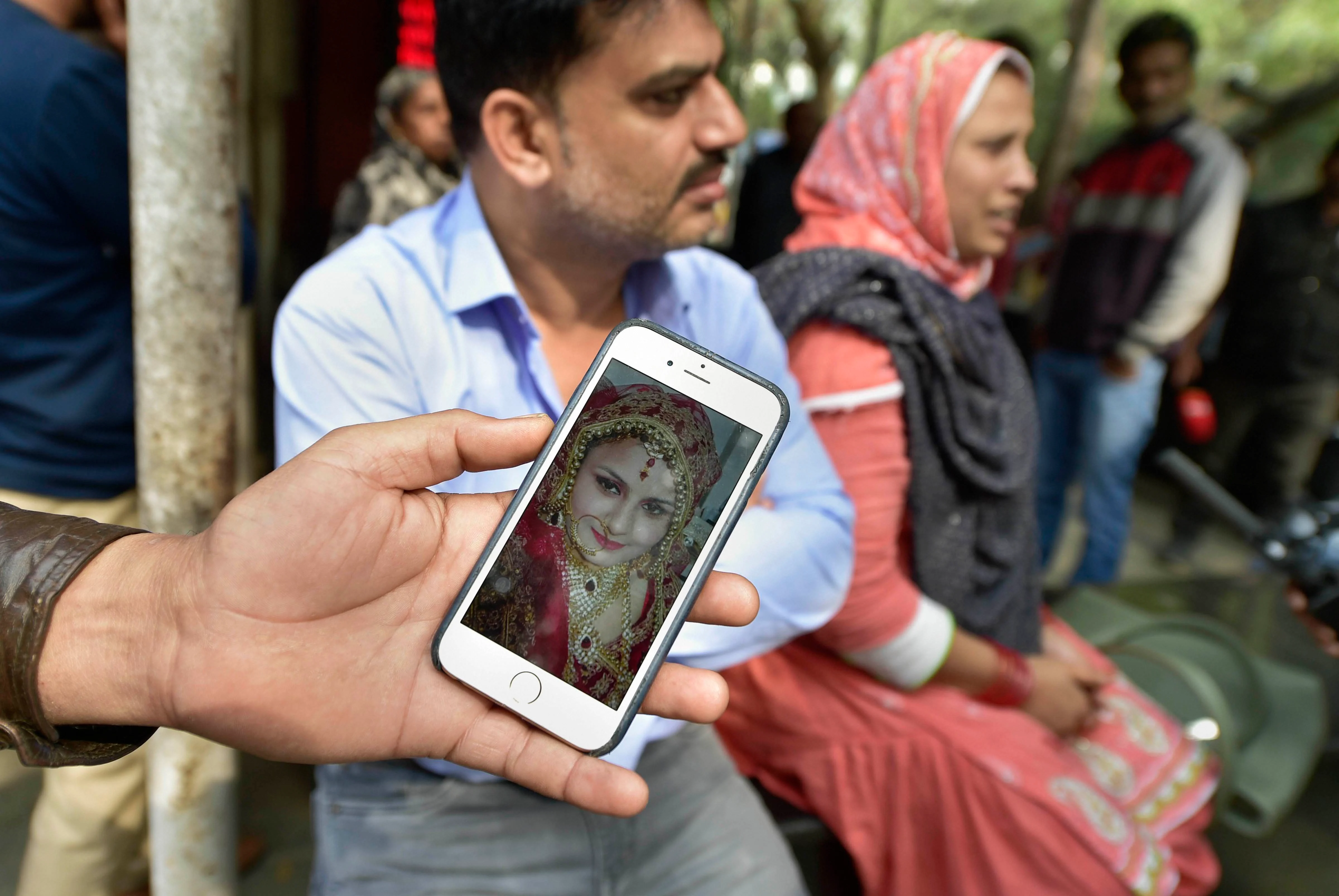 A relative shows a photograph of Tasneem Fatima, wife of Ashfaq Hussain (22), who was killed during the Delhi violence, outside the mortuary of GTB hospital in New Delhi on Thursday, Feb 27, 2020. (Photo: PTI)