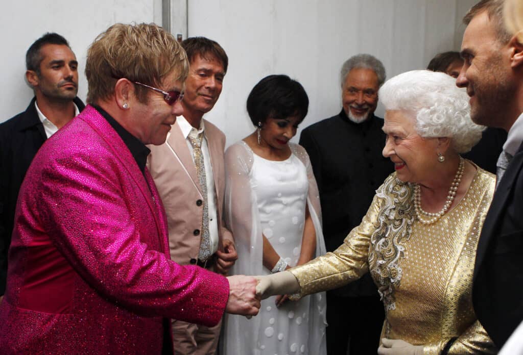 Queen Elizabeth II meets Sir Elton John backstage as British singer Robbie Williams (right) watches during the Diamond Jubilee Concert outside Buckingham Palace in London on 4 June 2012. | DAVE THOMPSON/POOL/AGENCE FRANCE-PRESSE