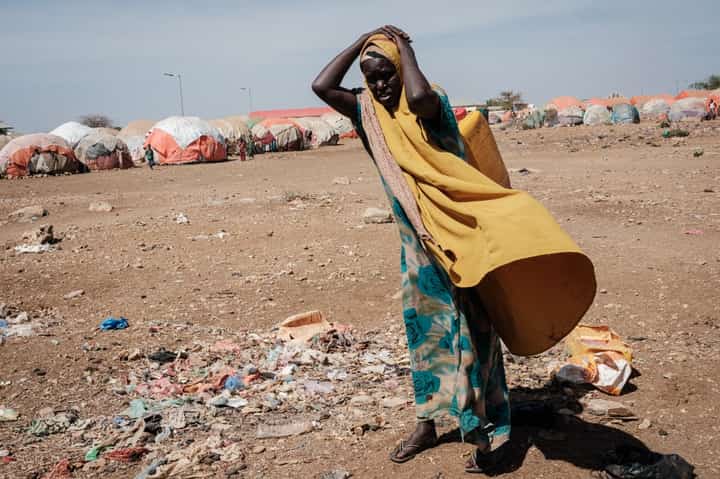 In this file photo taken on 13 February 2022, a woman carries a water container at a camp for internally displaced persons in Baidoa, Somalia. UN humanitarian chief Martin Griffiths warned on 5 September 2022 that Somalia was "at the door of famine" after being hit by four failed rainy seasons that has caused a devastating drought. (Photo by YASUYOSHI CHIBA / AFP)