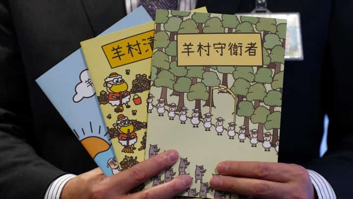 In this file photo, Hong Kong's senior superintendent Steve Li, from the city's new national security police unit, holds children's books which allegedly try to explain about the city's democracy movement, at a police press conference in Hong Kong on 22 July 2021, after five members of a pro-democracy Hong Kong union were arrested for sedition for publishing the titles. (Photo by DANIEL SUEN / AFP)