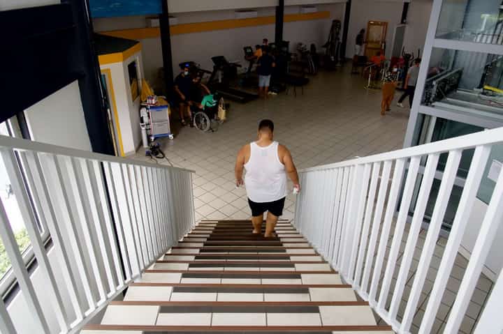 In this file photo, a patient climbs up and down to work on endurance and cardio at the Ora Ora follow-up care and rehabilitation center (Soins de Suite et Readaptation-SSR) for patients with overweight issues or obesity, in Pirae, Tahiti, French Polynesia, on 10 September 2021. Obesity conditions currently cost 2.2 percent of global GDP, and the biggest increases are expected to be seen in lower-resourced countries. (Photo by SULIANE FAVENNEC / AFP)