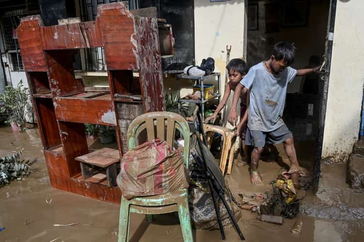 People clean their flooded home in the aftermath of Super Typhoon 'Karding' in San Mateo, Rizal province on 26 September 2022. (Photo by JAM STA ROSA / AFP)