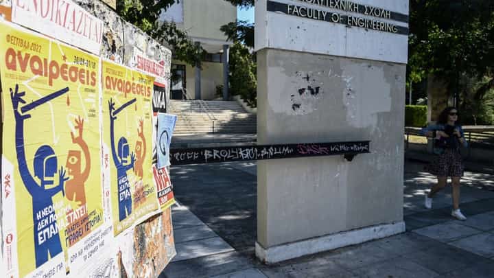 This picture taken on 29 September shows a student walking by banners against government plans to introduce policing on university campuses, in Thessalonikis Aristotelio university. - Over a year after it was conceived as a groundbreaking response to Greece's notoriously unruly universities, a special campus police force was officially deployed this month. Photo by Sakis MITROLIDIS / AFP