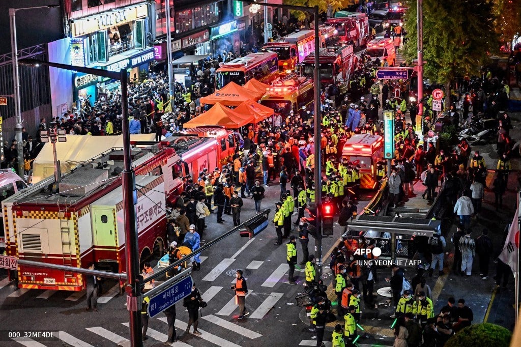 Onlookers, police and paramedics gather where dozens of people suffered cardiac arrest, in the popular nightlife district of Itaewon in Seoul on October 30, 2022. - Dozens of people suffered from cardiac arrest in the South Korean capital Seoul, after thousands of people crowded into narrow streets in the city's Itaewon neighbourhood to celebrate Halloween, local officials said. (Photo by JUNG YEON-JE / AFP)