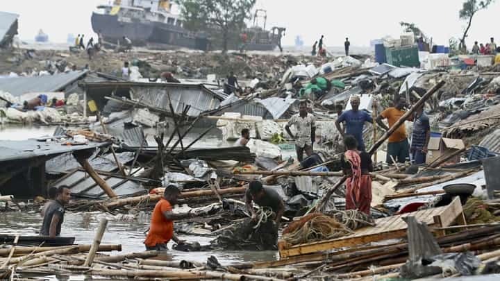Residents search for their belongings amid the debris of their collapsed huts after Cyclone Sitrang hit Chittagong on 25 October 2022. Around 10 million people were without power in 15 coastal districts of Bangladesh, while schools were shut across the southern and southwestern regions. (Photo by RABIN CHOWDHURY / AFP)