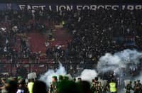 This picture taken on 1 October 2022 shows security personnel (lower) on the pitch after a football match between Arema FC and Persebaya Surabaya at Kanjuruhan stadium in Malang, East Java. At least 127 people died at a football stadium in Indonesia late on 1 October when fans invaded the pitch and police responded with tear gas, triggering a stampede, officials said. (Photo by AFP)