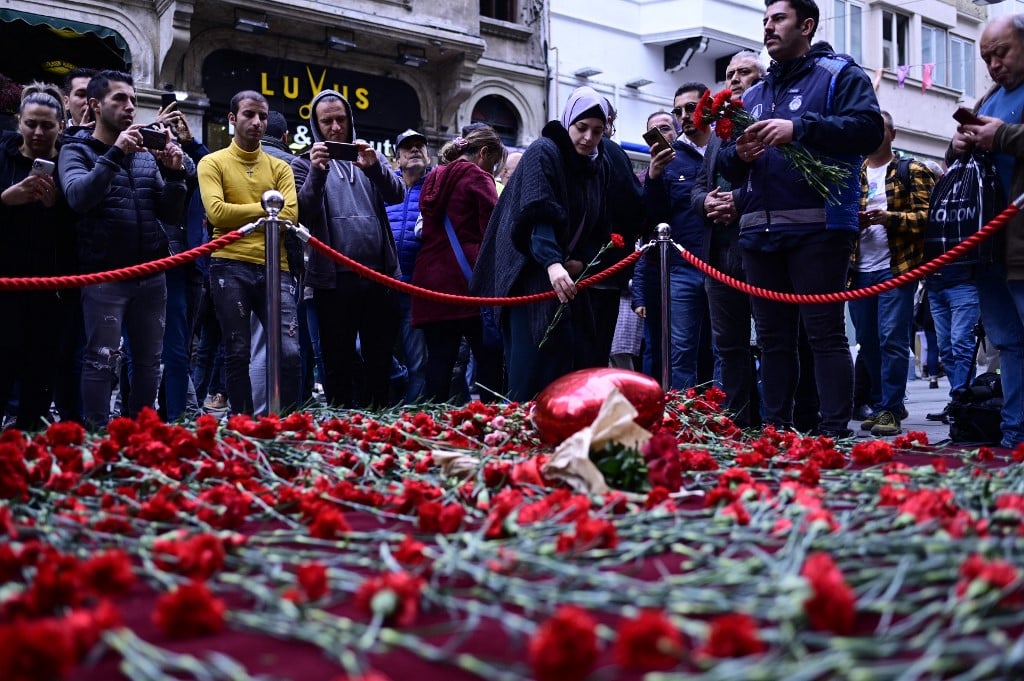 People lay flowers at a makeshift memorial for the victims of the 13 November explosion at the busy shopping street of Istiklal in Istanbul on 14 November 2022. (Photo by YASIN AKGUL / AFP)