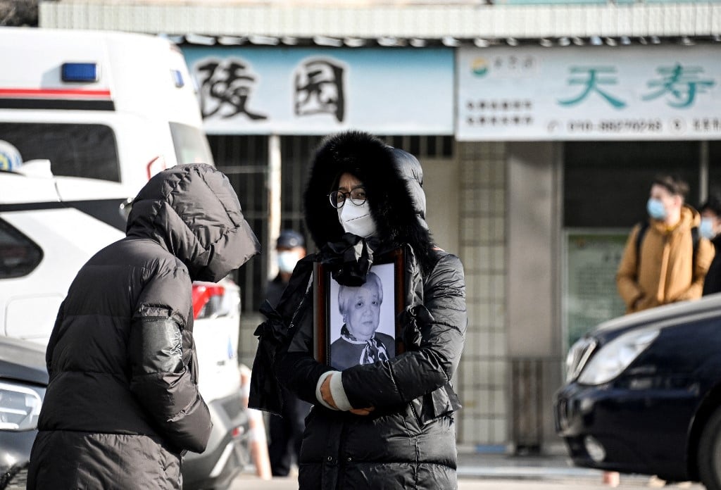 A woman holds a picture frame of a loved one at a crematorium in Beijing on December 20, 2022. - Workers at Beijing crematoriums said on December 16 they are overwhelmed as China faces a surge in Covid cases that authorities warn could hit its underdeveloped rural hinterland during upcoming public holidays. Photo by Noel  Celis / AFP