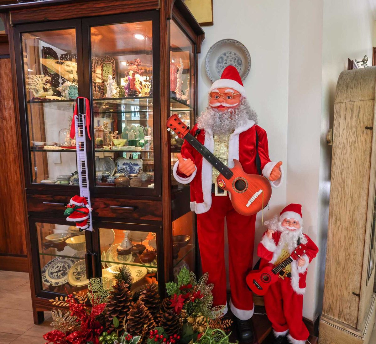 Big and Small Santa Clauses stand beside a display cabinet filled with Frannie's miniature Orientalia collection