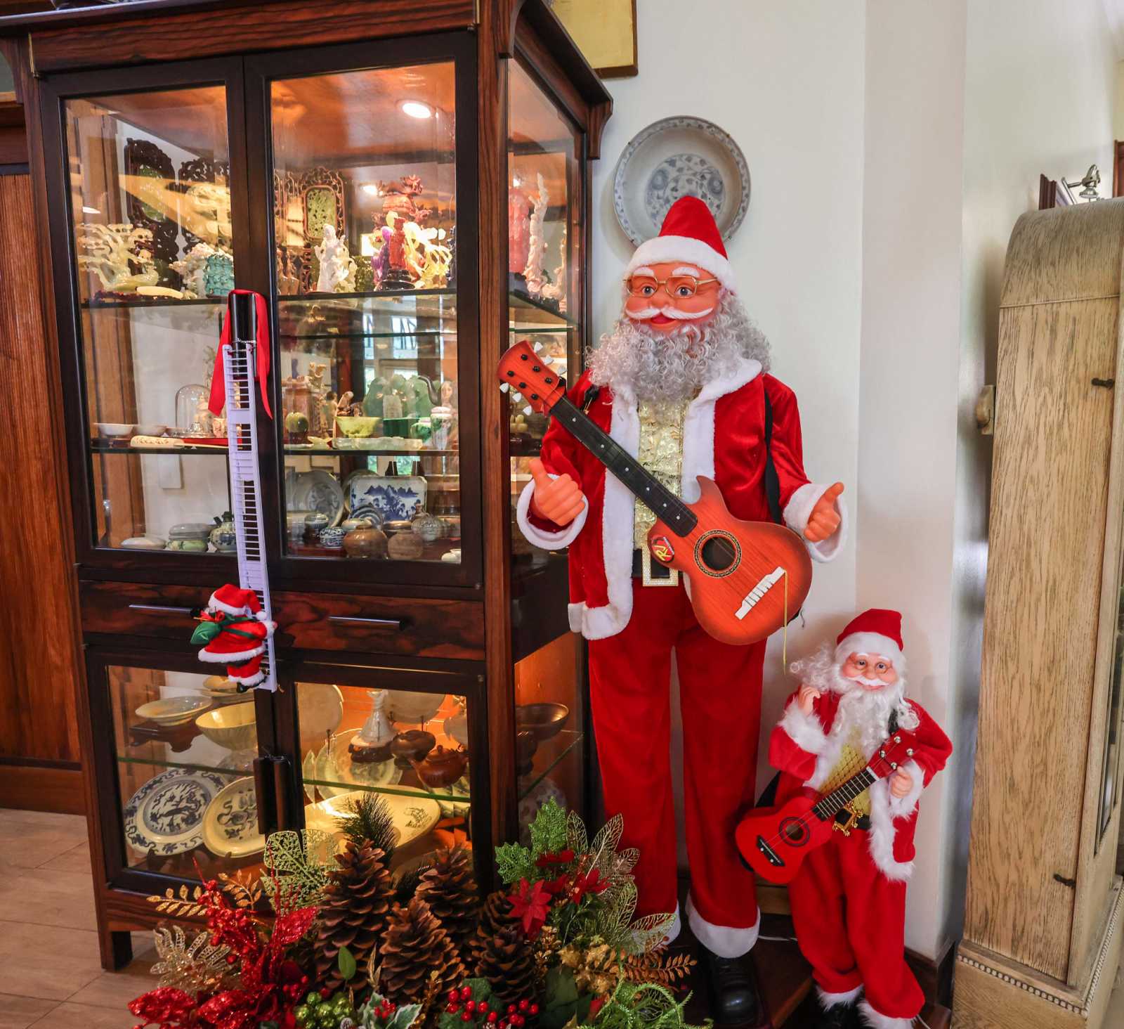 Big and Small Santa Clauses stand beside a display cabinet filled with Frannie's miniature Orientalia collection