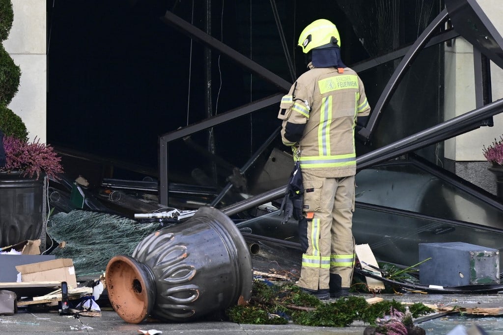 A firefighter stands amid debris in front of the Radisson Blu hotel after a huge aquarium located in the hotel's lobby burst on 16 December 2022 in Berlin. (Photo by JOHN MACDOUGALL / AFP)