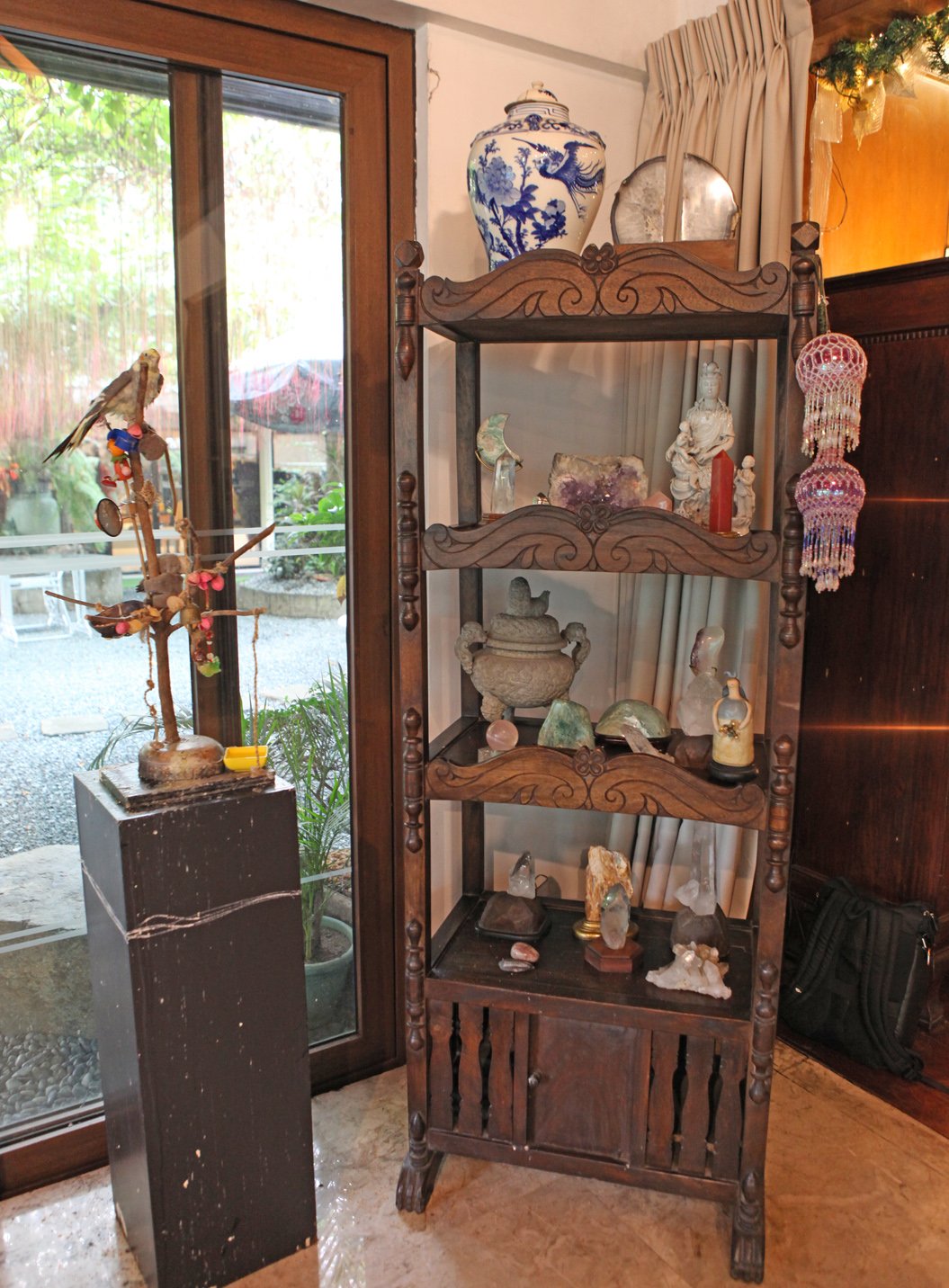 A CORNER antique shelf contains oriental artifacts.