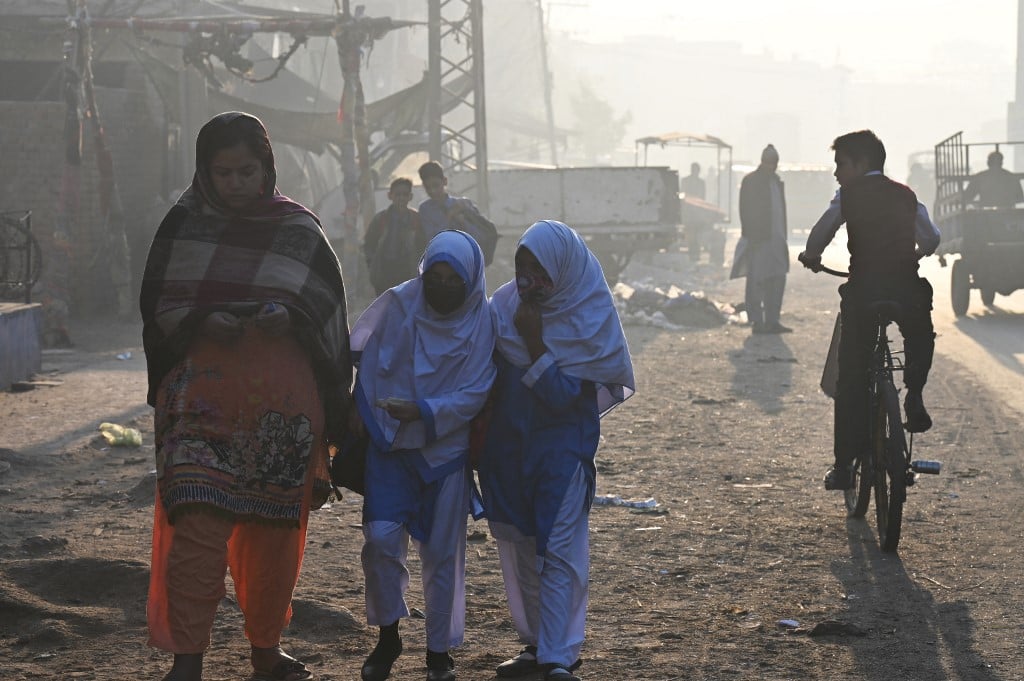 Children walk to school amid heavy smog conditions in Lahore on 7 December 2022. (Photo by ARIF ALI / AFP)