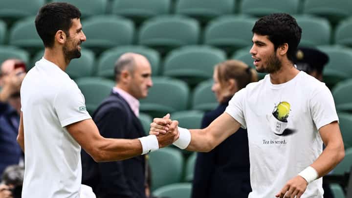 Serbia's Novak Djokovic (L) shakes hands with Spain's Carlos Alcaraz during a practise session prior to their men's singles semi-finals tennis matches on the twelfth day of the 2023 Wimbledon Championships at The All England Lawn Tennis Club in Wimbledon, southwest London, on July 14, 2023. (Photo by SEBASTIEN BOZON / AFP) / RESTRICTED TO EDITORIAL USE