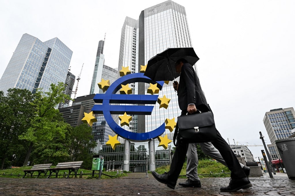 FILE PHOTO: A man shelters from the rain under an umbrella as he walks past the Euro currency sign in front of the former European Central Bank (ECB) building in Frankfurt am Main, western Germany, on 27 July 2023 ahead of thr ECB's monthly announcement on eurozone monetary policy. (Photo by Kirill KUDRYAVTSEV / AFP)