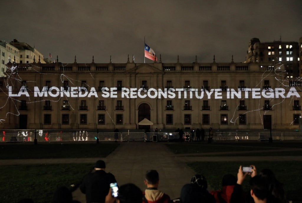 The phrase "La Moneda is Reconstituted in its Entirety" is seen as commemorative images are projected on the facade of La Moneda Presidential Palace in Santiago on 11 September 2023, on the 50th anniversary of the coup d'etat that brought Augusto Pinochet to power. (Photo by Javier TORRES / AFP)