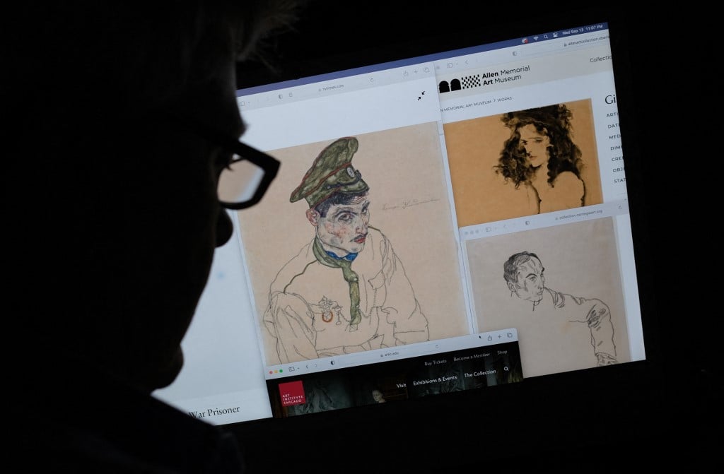 This photo illustration created in Los Angeles, California, on 13 September 2023, shows a person looking on a computer screen at artwork by Austrian Expressionist Egon Schiele entitled "Russian War Prisoner" (L), "Portrait of a Man" (R) and "Girl With Black Hair" (top), which were seized by investigators after the Manhattan district attorneys office issued warrants. US authorities seized three artworks sought by the heirs of a Jewish art collector who died in the Holocaust, officials said on 14 September 2023. (Photo by Chris DELMAS / AFP)