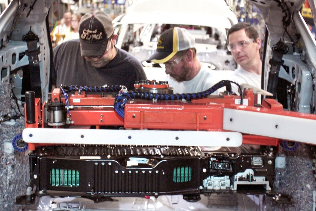 FILE PHOTO: Ford workers load a battery into a Ford C-MAX plug-in hybrid vehicle at the Michigan Assembly Plant. (Photo by BILL PUGLIANO / GETTY IMAGES NORTH AMERICA / Getty Images via AFP)