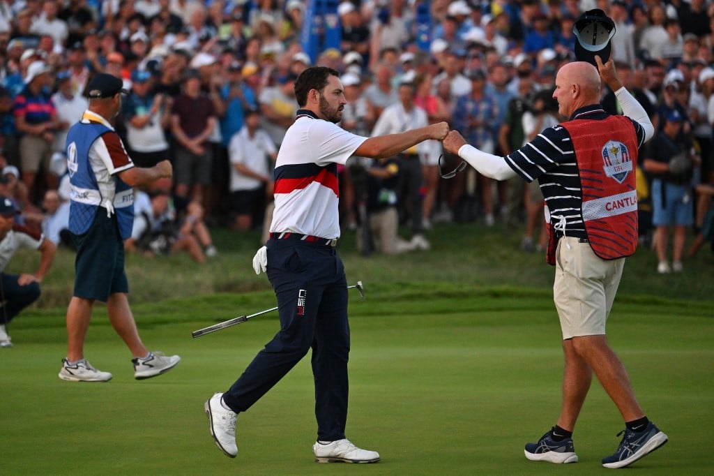 US golfer, Patrick Cantlay (C) celebrates with his caddie Joe LaCava (R) after holing his birdie putt to win the hole and the match on the 18th green with US golfer, Wyndham Clark during their four-ball match against Europe's Northern Irish golfer, Rory McIlroy and Europe's English golfer, Matt Fitzpatrick on the second day of play in the 44th Ryder Cup at the Marco Simone Golf and Country Club in Rome on 30 September  2023. (AFP)
